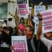 Massa aksi mengangkat poster tuntutan audit MBG dan kritik kondisi hidup saat demo di depan kantor BGN Jakarta
